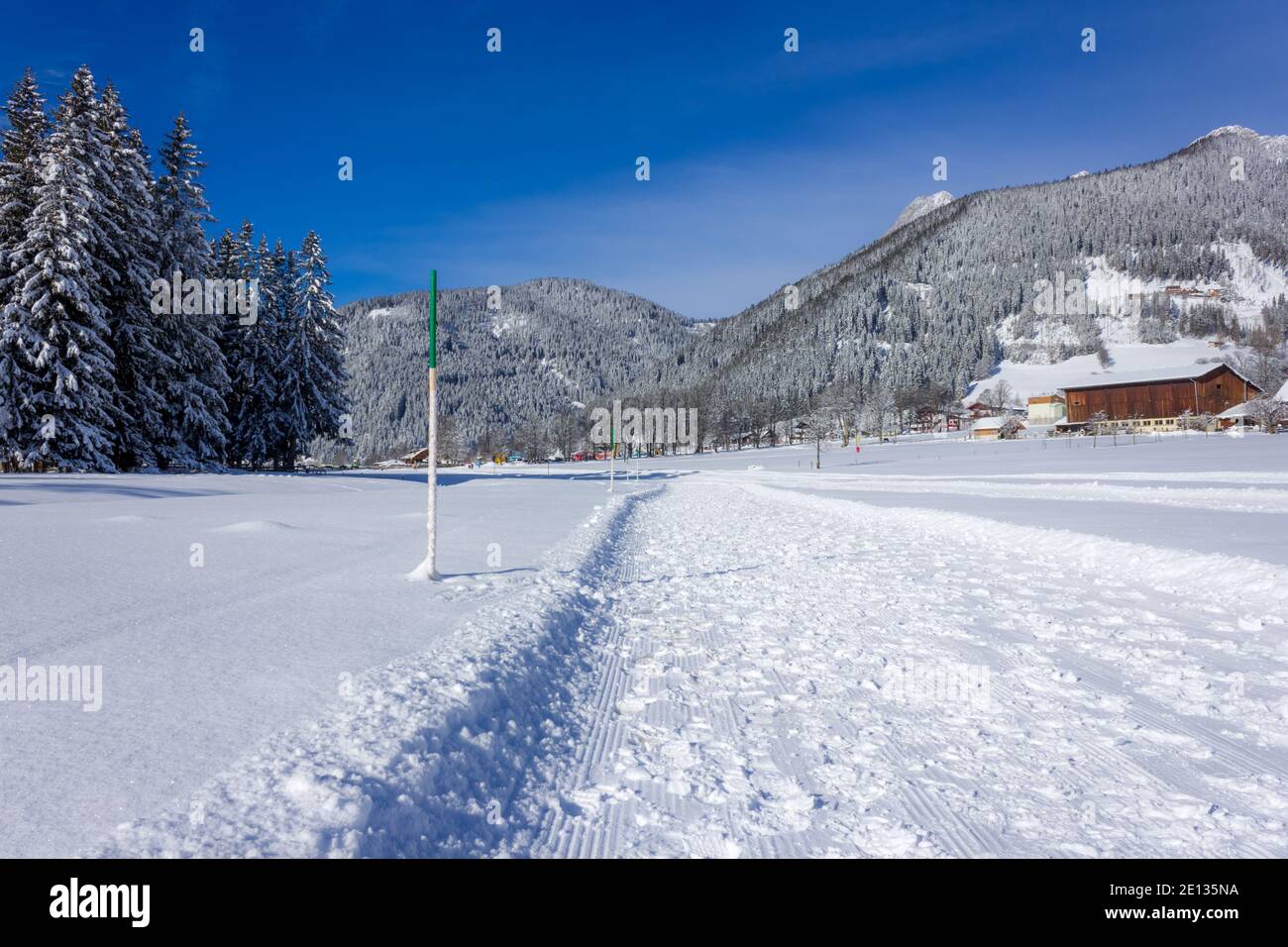 Verschneite Winterlandschaft in den Alpen mit Wanderweg und mehreren Bergen im Hintergrund (Ramsau am Dachstein, Österreich) Stockfoto