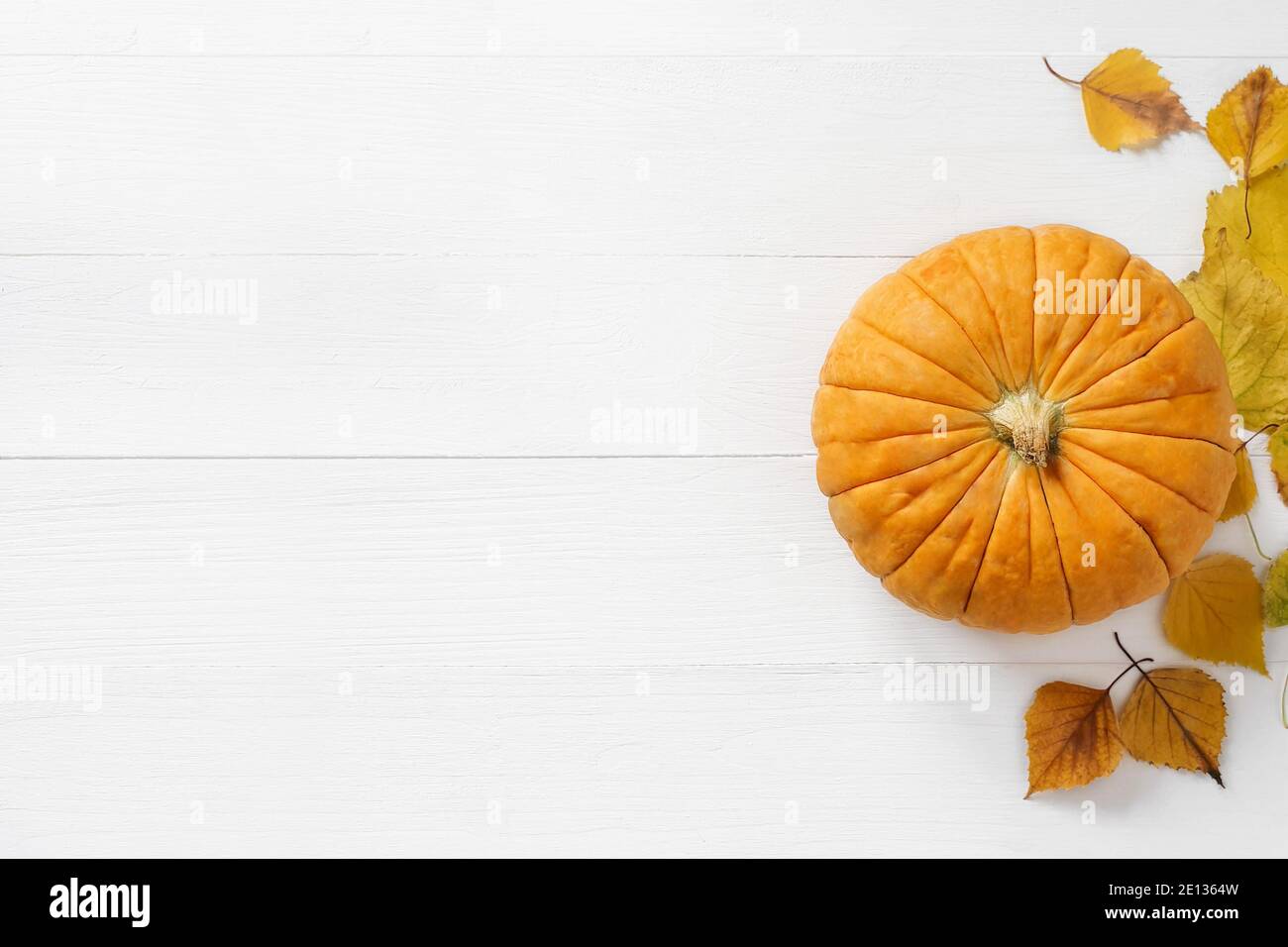 Draufsicht auf orange / gelbe Kürbis und Herbst gelbe Blätter auf einem schäbigen weißen Brett Holzhintergrund. Herbst, Herbst, halloween Konzept. Trendschatten, Stockfoto