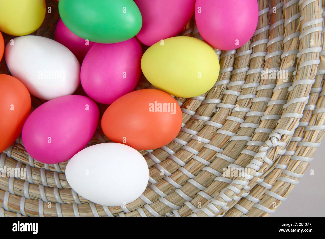 Bunte Ostereier, in einem strohkorb vor grauem Hintergrund. Stockfoto