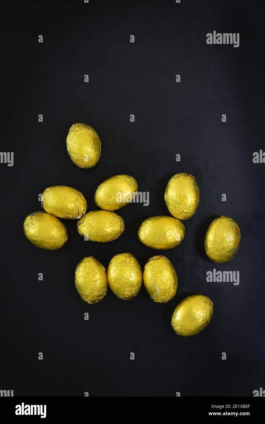 Kleine Gruppe von goldgelben ostern Mini-Eier, die Folie verpackt sind. Die befinden sich auf einem schwarzen und grauen Hintergrund, mit Platz für Kopien. Stockfoto
