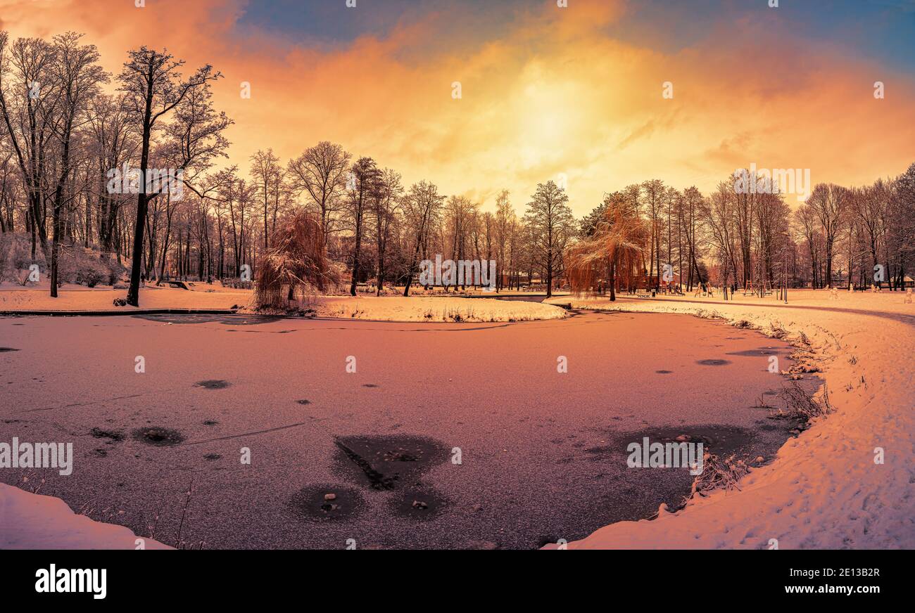 Sonnenuntergang über Park mit kleinem See und mit Schnee bedeckt Bäume Stockfoto