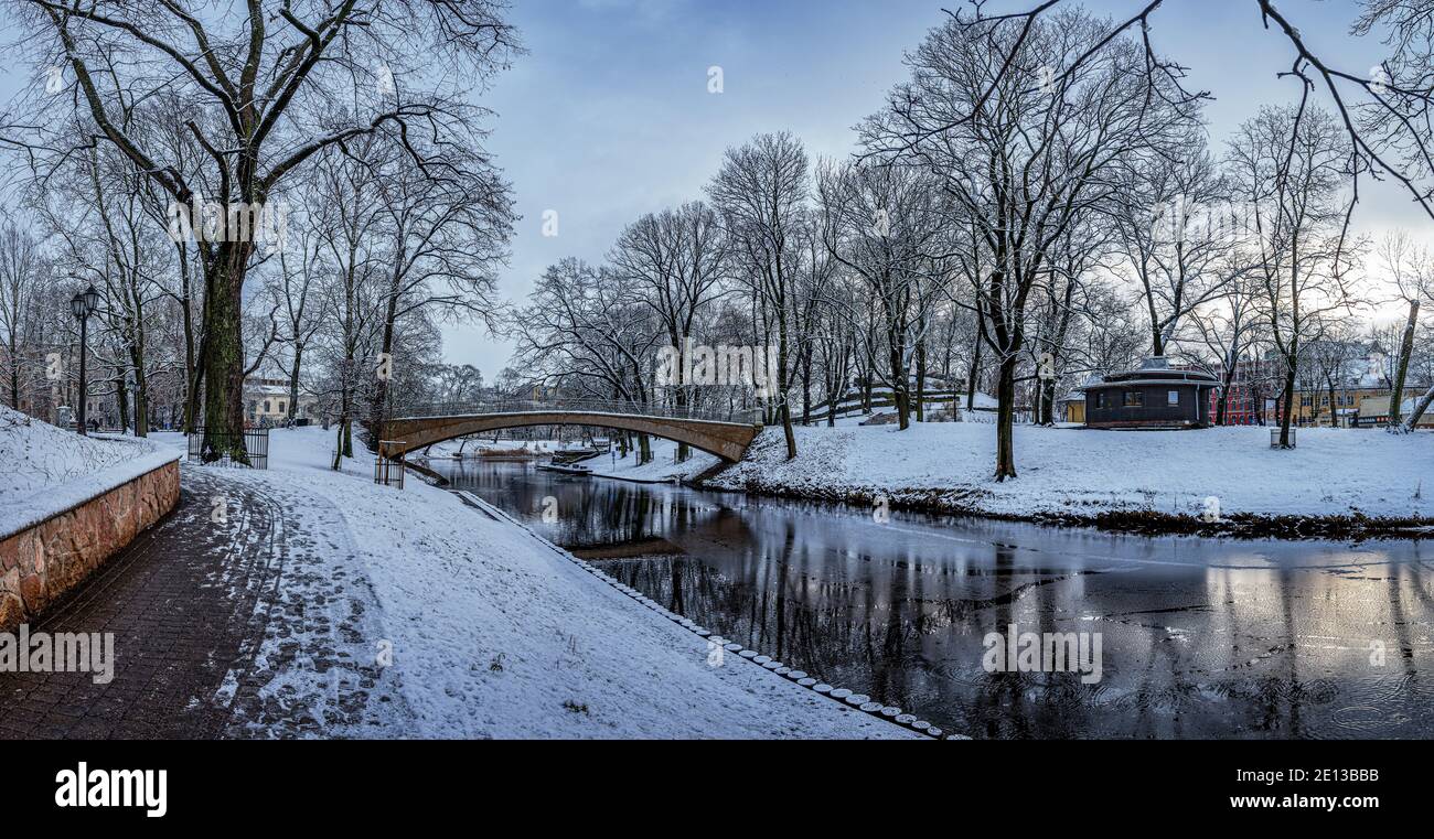 Panorama-Winterlandschaft in verschneiten Park mit schöner Brücke über kleinen Kanal, Straßenbeleuchtung und mit Schnee bedeckt. Blick auf den Bastion Hill Park Stockfoto