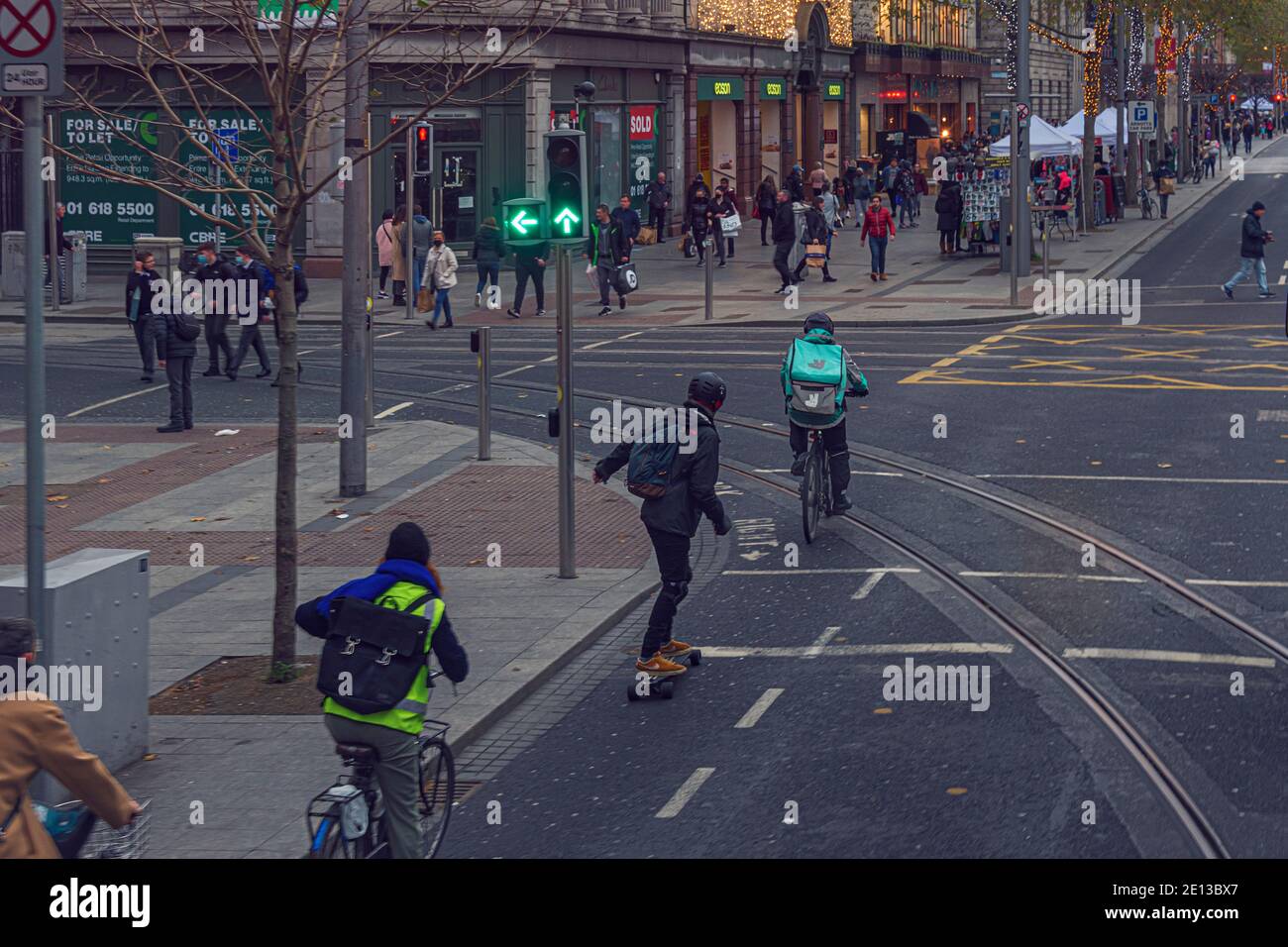 Alternativer Transport. Menschen auf Fahrrädern, Roller und Skateboard Reiten in O'Connell Street. Dublin, Irland. Stockfoto