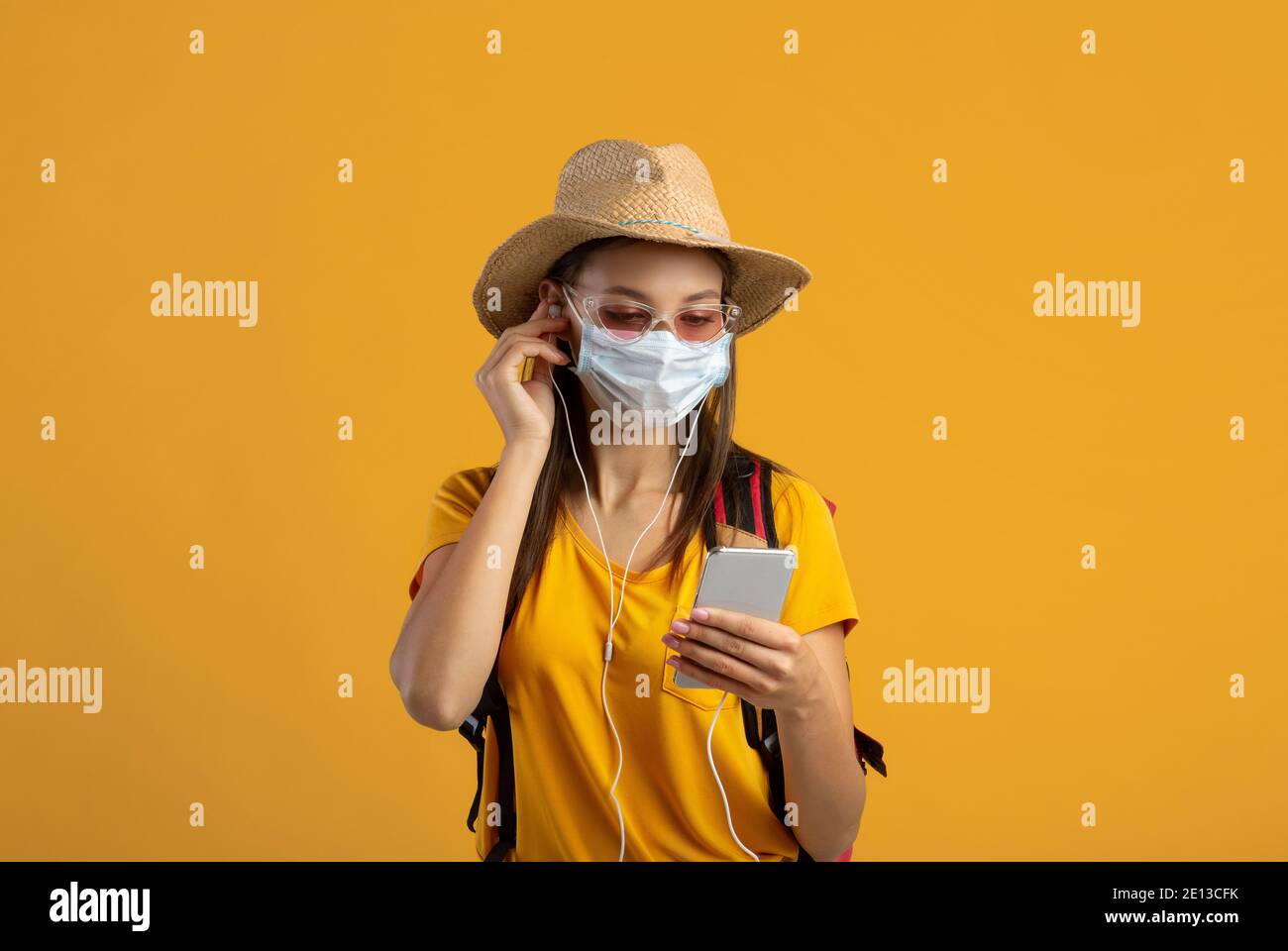 Weibliche Reisende in Gesichtsmaske hören Musik auf dem Smartphone Stockfoto