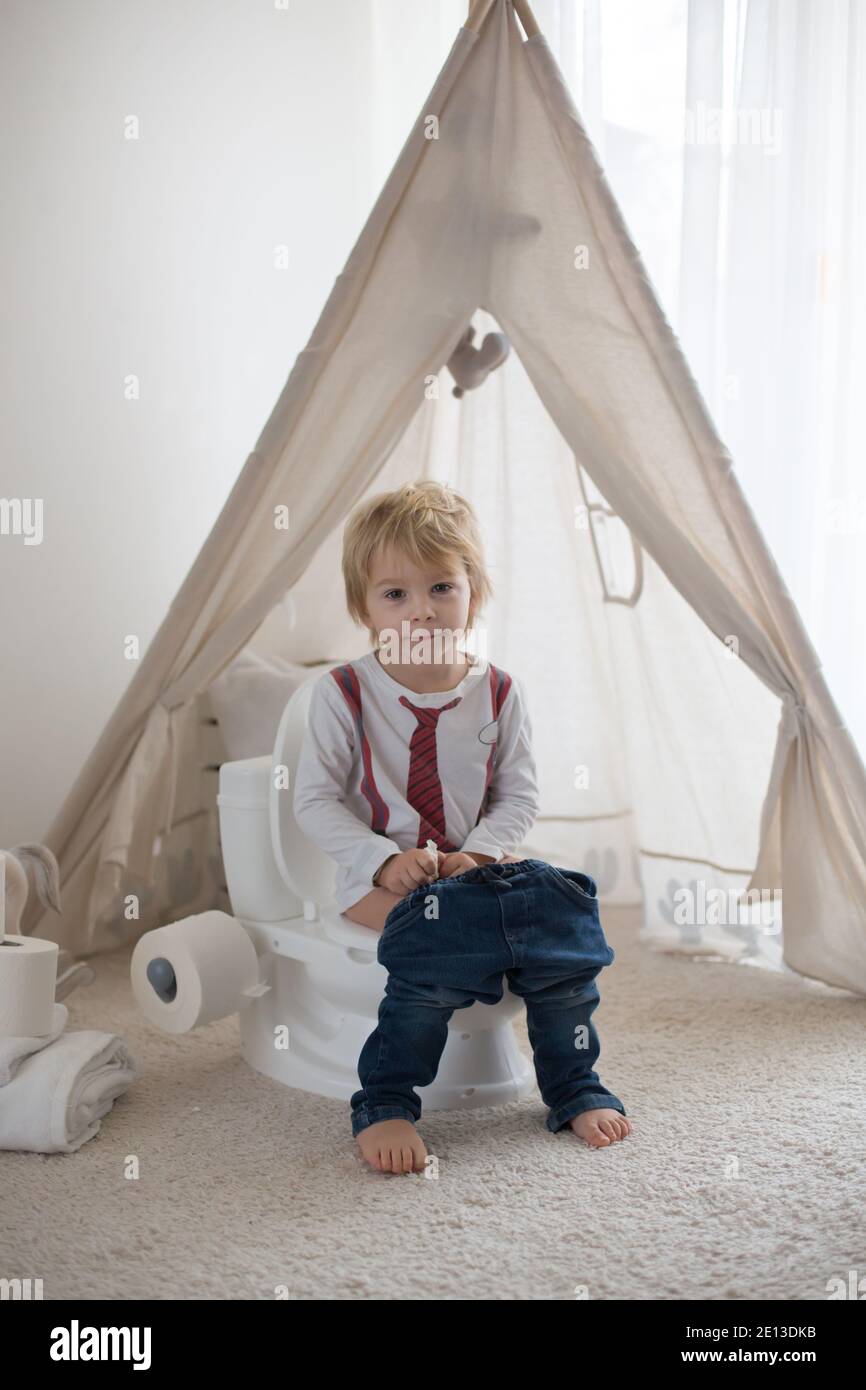 Nettes Kleinkind Kind, Junge, sitzt auf einem Baby-WC Töpfchen, spielt mit Spielzeug Stockfoto