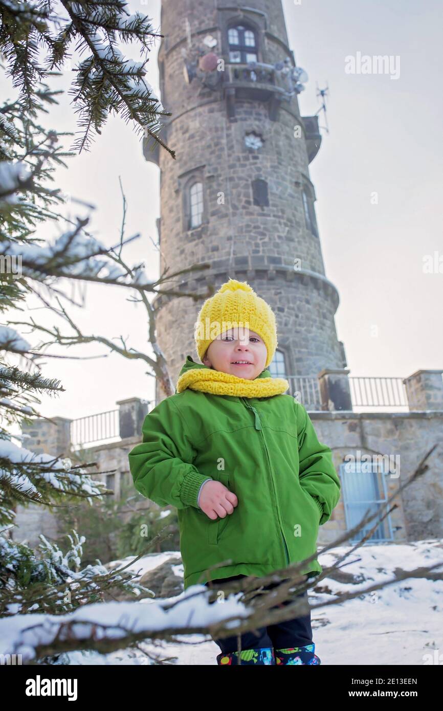 Niedliches Kleinkind Kind, süßer Junge, posiert vor der schönen Winteransicht von Milchbäumen und Felsen bei Sonnenuntergang, gefrorenen Aussichtsturm Sneznik, Bohemian SW Stockfoto