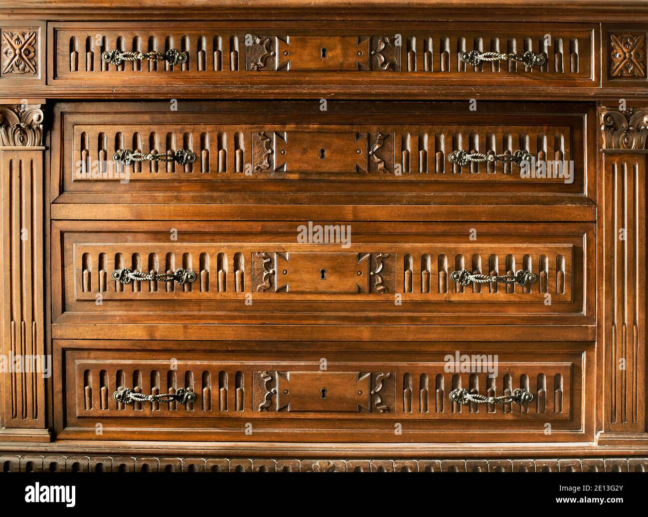 Kommode aus Vintage-Holz mit geschnitzten Details, Messinggriffen und zentralen Schlüssellochen in Nahaufnahme Detail Stockfoto