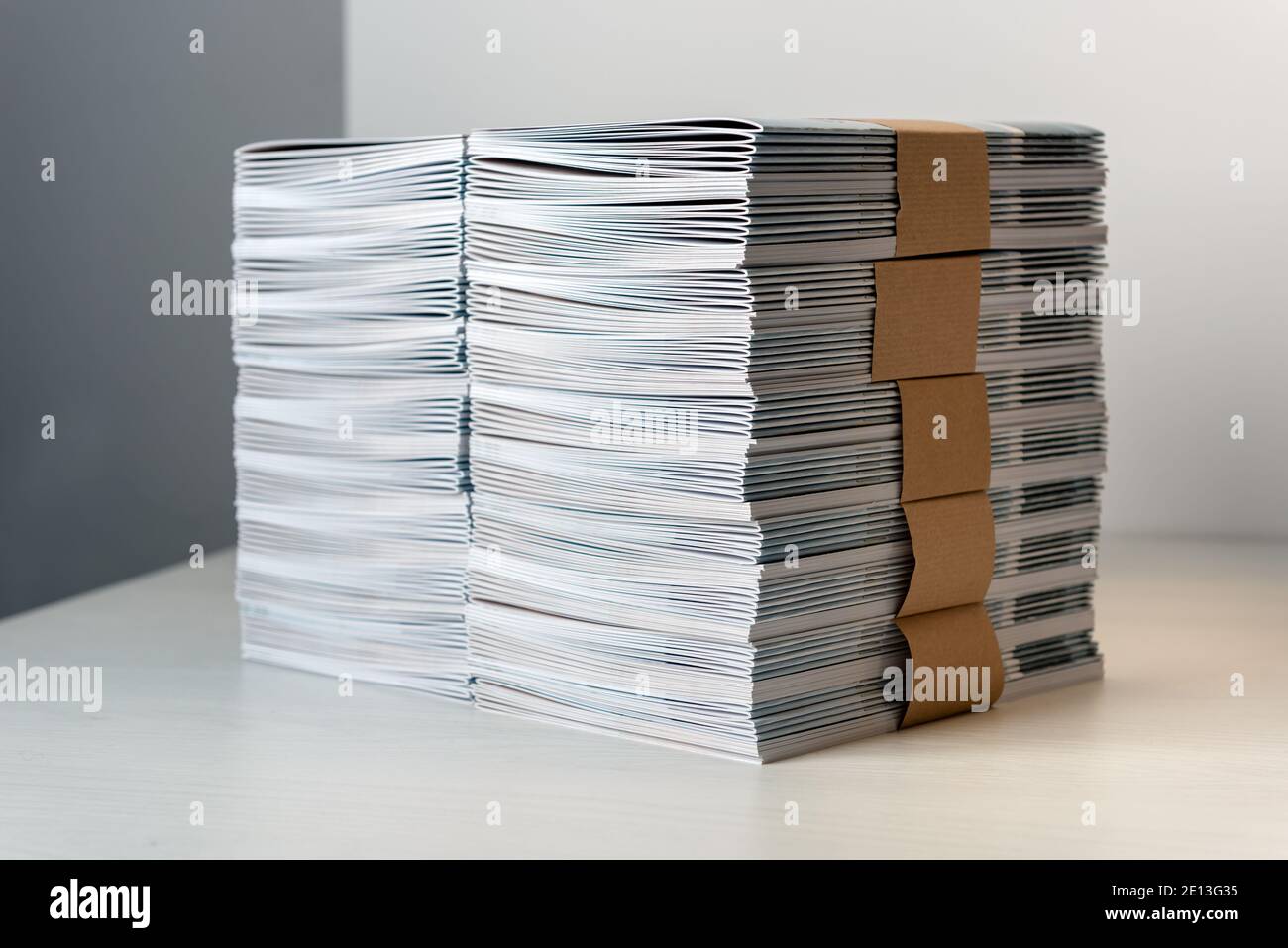 Bündel von neu gedruckten Katalogen mit braunem Papier befestigt angeordnet Ordentlich in einem Stapel auf einem weißen Tisch Stockfoto