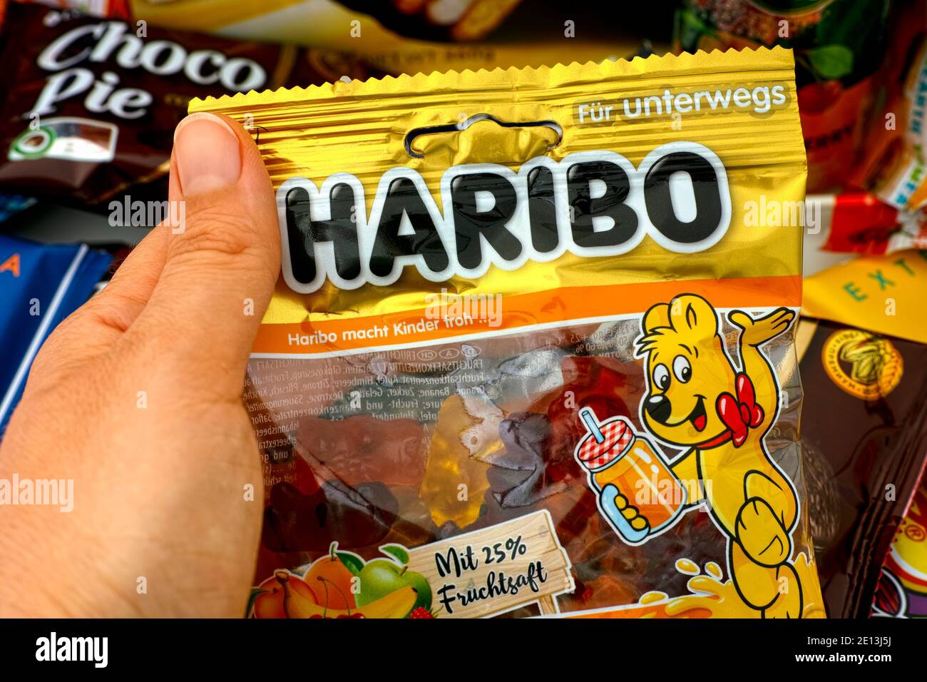 Tambow, Russische Föderation - 30. Oktober 2020 Person Hand nehmen Packung Haribo Bären Gummy Candy. Viele süße Snacks und Getränke im Hintergrund. Stockfoto