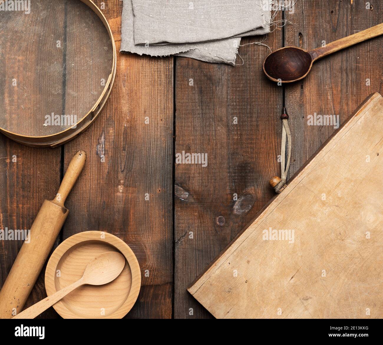 Sehr alte Holzküche Vintage-Artikel: Sieb, Nudelholz, leere Löffel und runde Teller auf braunem Holztisch, Draufsicht Stockfoto