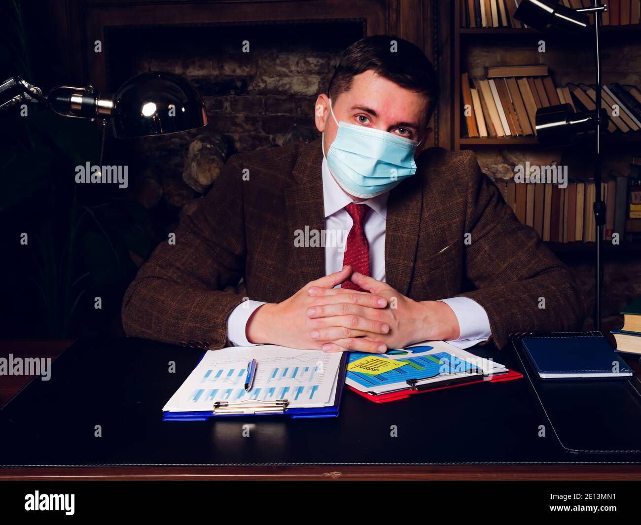 Porträt eines Geschäftsmannes in einer medizinischen Maske am Tisch sitzen. Stockfoto