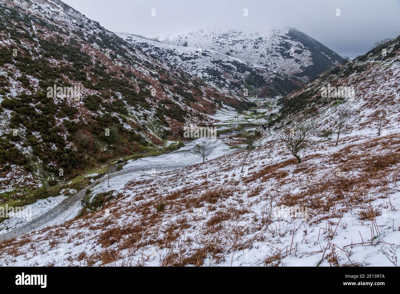 Ein Winterfoto eines Tals, das zum Gipfel des Long Mynd in Shropshire, England, führt. Menschen, die im Tal wandern. Stockfoto