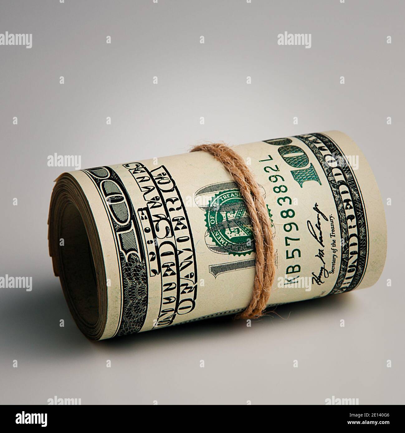 Rolle von hundert amerikanischen Dollar Nahaufnahme auf einem grauen Hintergrund. Nahaufnahme, freier Platz für Bildunterschriften und Text. Stockfoto