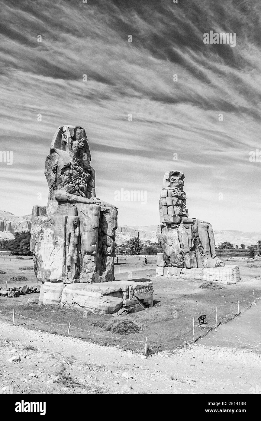 Dies ist die archäologische Stätte 1350BC an den Memnonkolossen des alten Ägyptens, nicht weit vom Nil und der Stadt Luxor, die früher als Theben bekannt war. Die Statuen sind vom Pharao Amenhotep III, es gibt zwei kleinere Statuen an seinen Füßen, eine ist seine Mutter, die andere seine Frau. Ursprünglich gebaut, um den Eingang zum Amenoteps Tempel gegen das Böse zu schützen, wurden sie auch gesehen, um das Westufer des Nils zu bewachen. Die Kolossi haben unter schweren Erdbebenschäden gelitten, aber nach 3500 Jahren stehen bleiben. Stockfoto