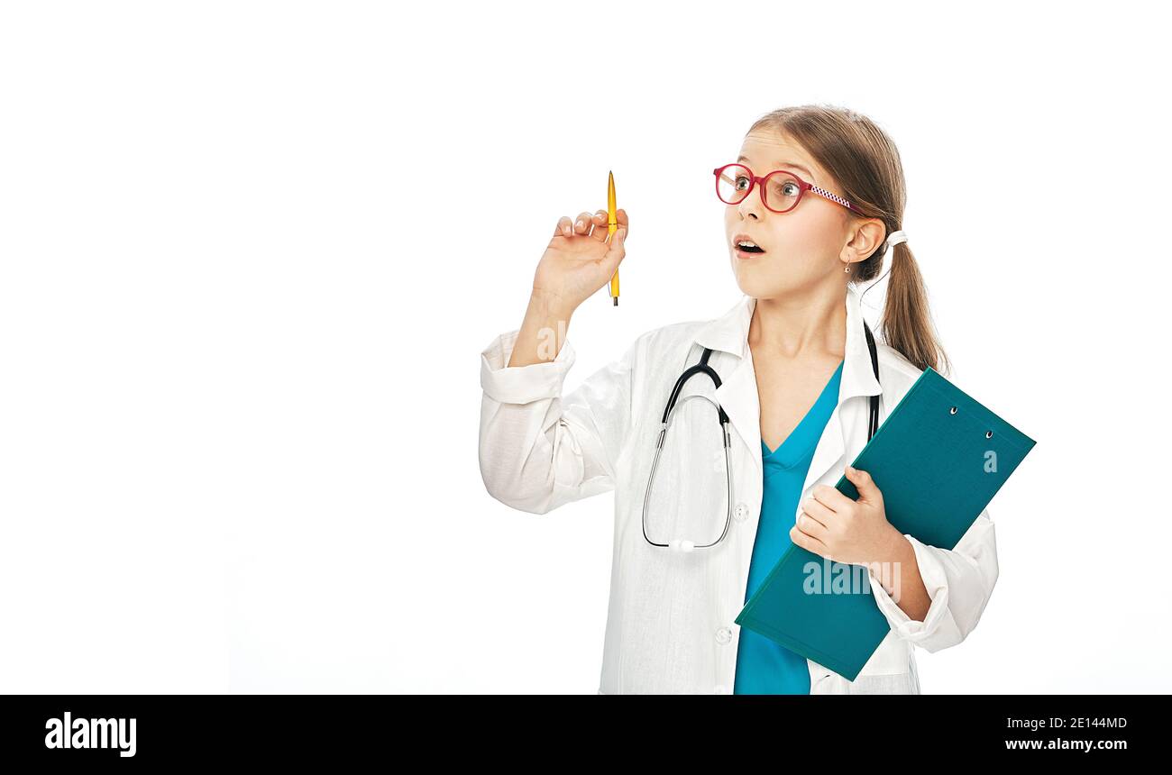 Nettes Mädchen trägt Arztmantel und Stethoskop, mit überraschenden Emotionen auf ihrem Gesicht, zeigen Stift in leeren Raum auf dem Hintergrund. Stockfoto
