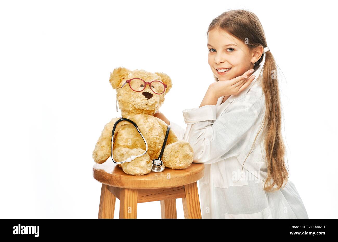 Nettes Mädchen spielen in Arzt Beruf mit einem Bär Spielzeug. Kinderhobby und zukünftige medizinische Beschäftigung Stockfoto