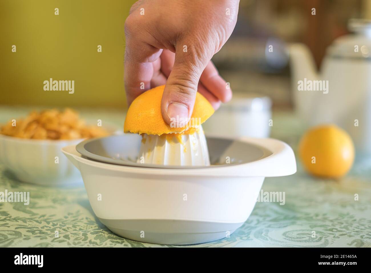 Mann quetscht frisches Orangenobst auf dem Entsafter, gesundes Essen Frühstück, morgendliche Diät Stockfoto