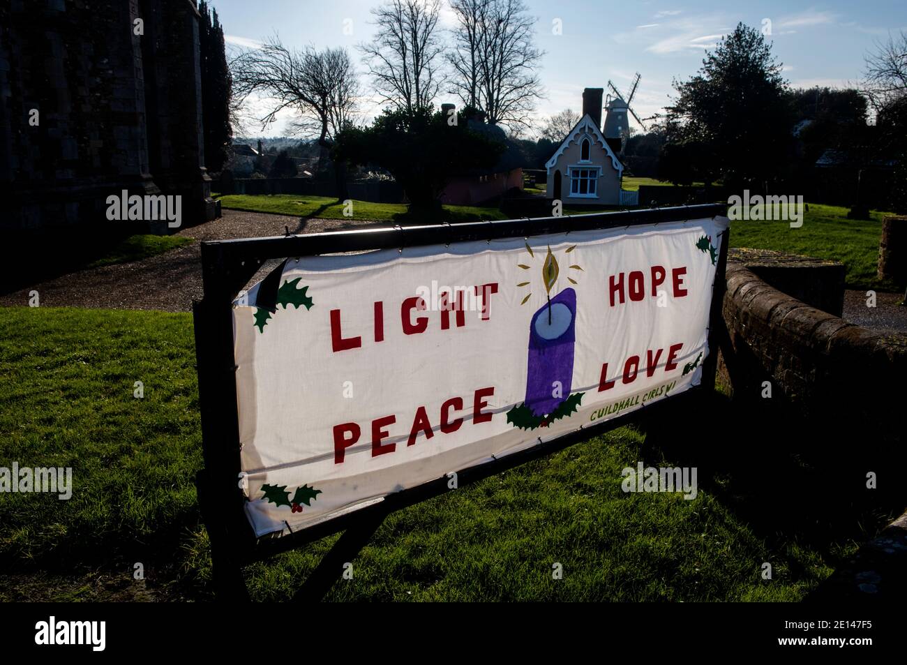 Thaxted Essex England UK Januar 2021 Thaxted Kirche und Licht, Hoffnung, Frieden, Liebe Zeichen mit Alms House im Hintergrund Stockfoto