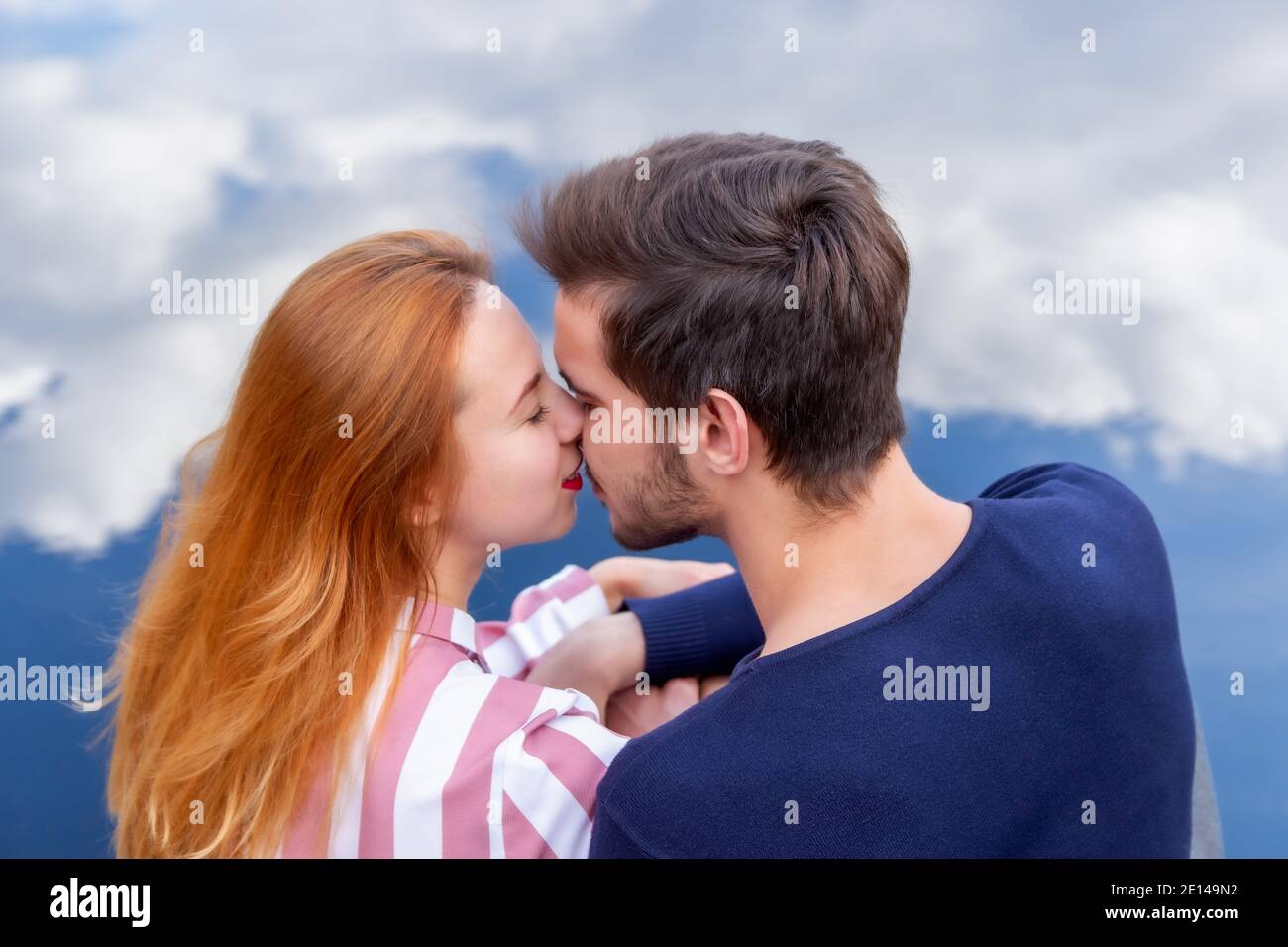 Ein zarter Kuss über den Wolken eines Mannes und Eine blonde Frau mit goldenen Haaren Stockfoto