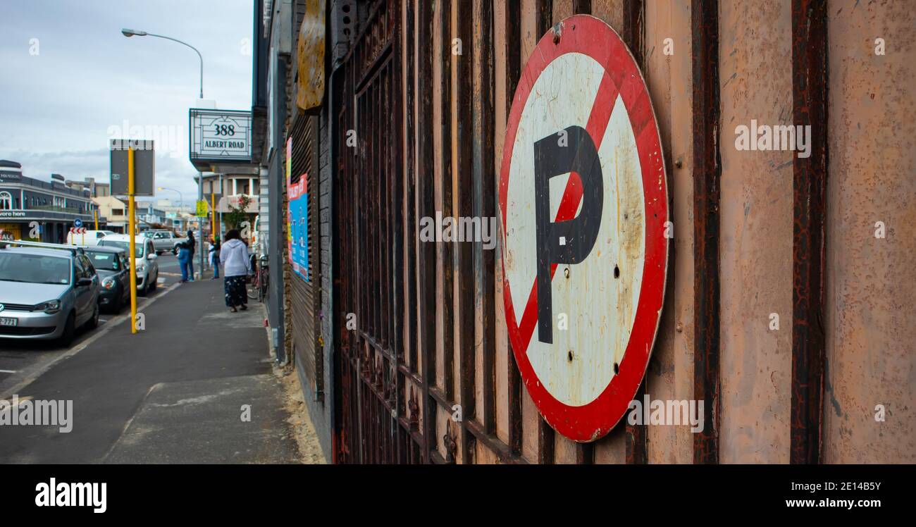 Woodstock- Cape Town, South Africa - 14/11/2020 Rusty 'No Parking' Schild an einem Tor auf der Albert Road. Menschen und fließender Verkehr im Hintergrund. Stockfoto