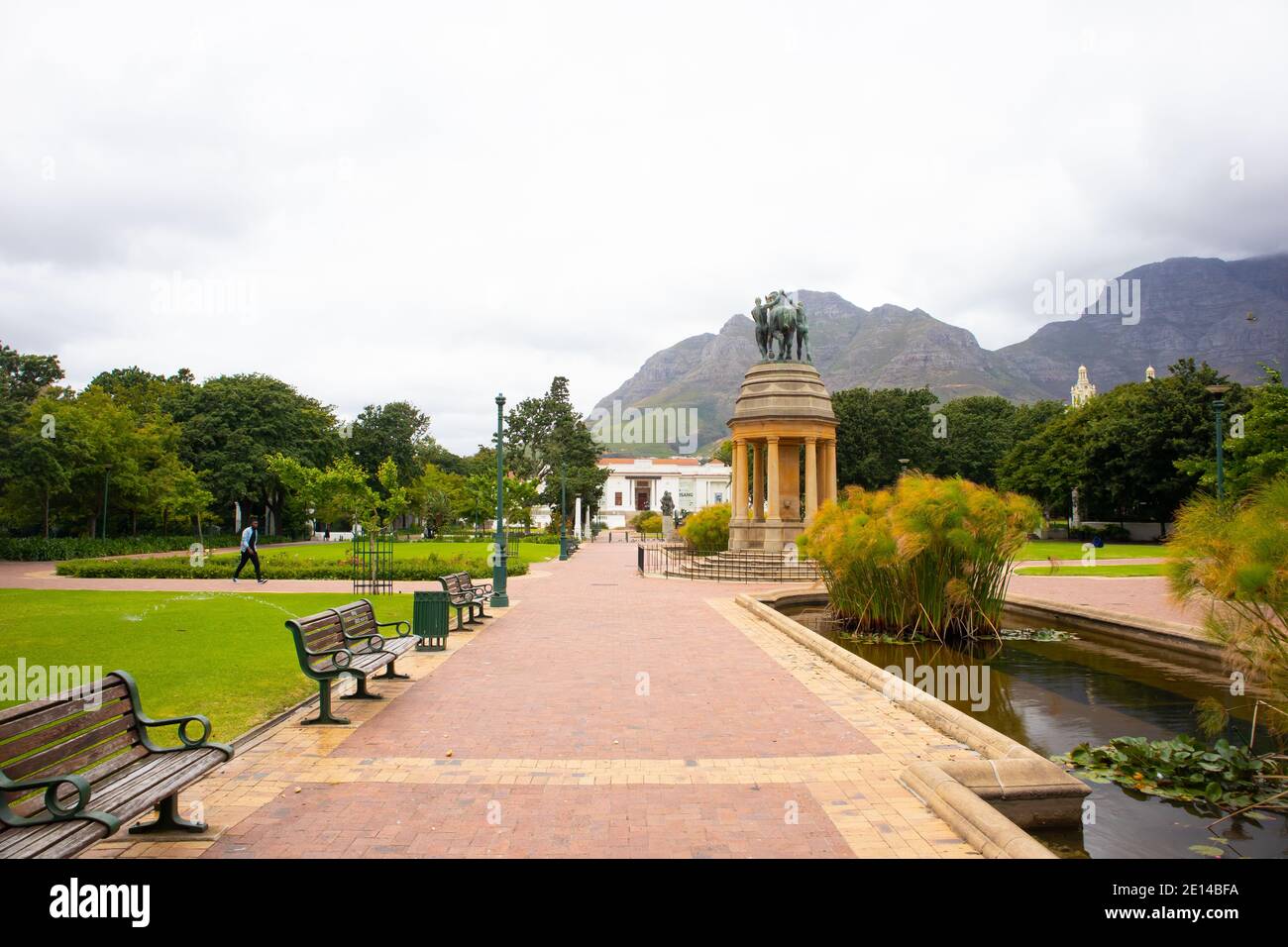 Gärten - Kapstadt, Südafrika - 23/11/2020 Gärten an einem bewölkten Tag. Pferdestatue, Grün und wolkenbedeckten Berg. Mann in Gesichtsmaske, der vorbei geht Stockfoto