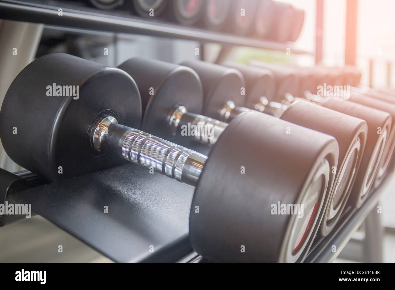 Schwarze Kurzhantel-Set. Nahaufnahme von vielen Metall-Hanteln auf einer Ablage im Sport-Fitness-Center. Stockfoto