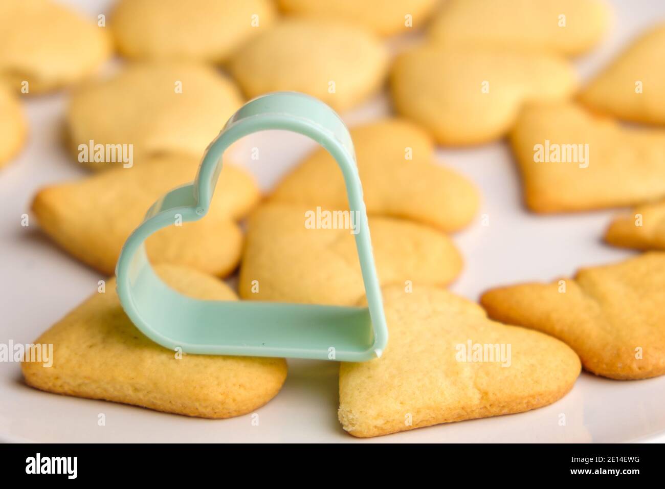 Hausgemachte Kekse für den Valentinstag mit grüner Kunststoff-Backform. Stockfoto