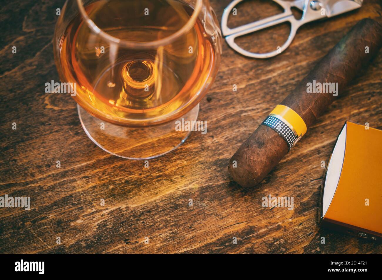 Tabak und Alkohol. Zigarre und Brandy auf einem Holztisch, Nahaufnahme. Kubanische Qualität Zigarre und Whiskey, Rauchen und Trinken Luxus Lifestyle Stockfoto