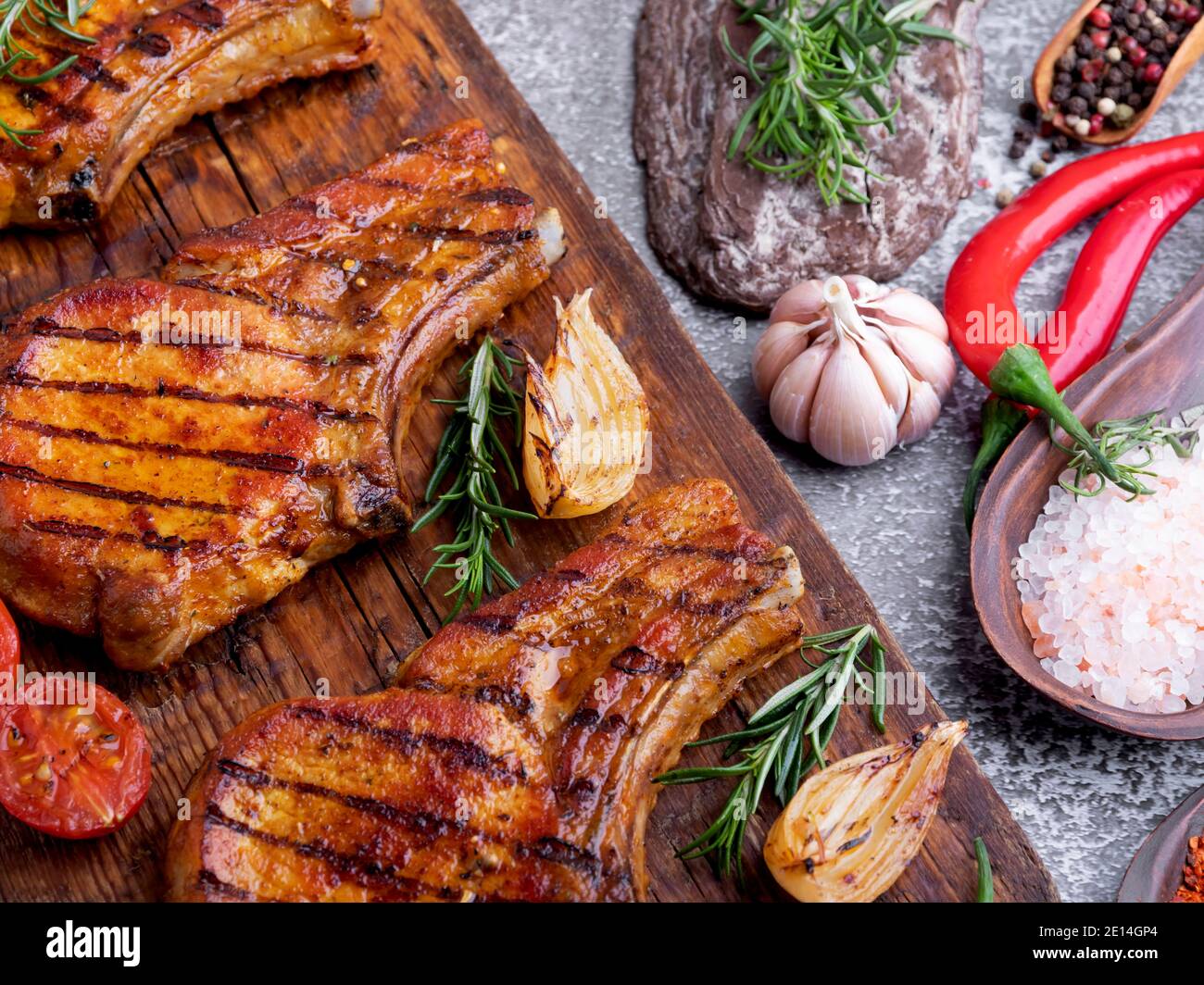 Gekochtes gegrilltes Fleisch Schweinefleisch, Rindfleisch, Hacken Knochen, Schneidebrett Gewürze Tomate, Rosmarin Stockfoto