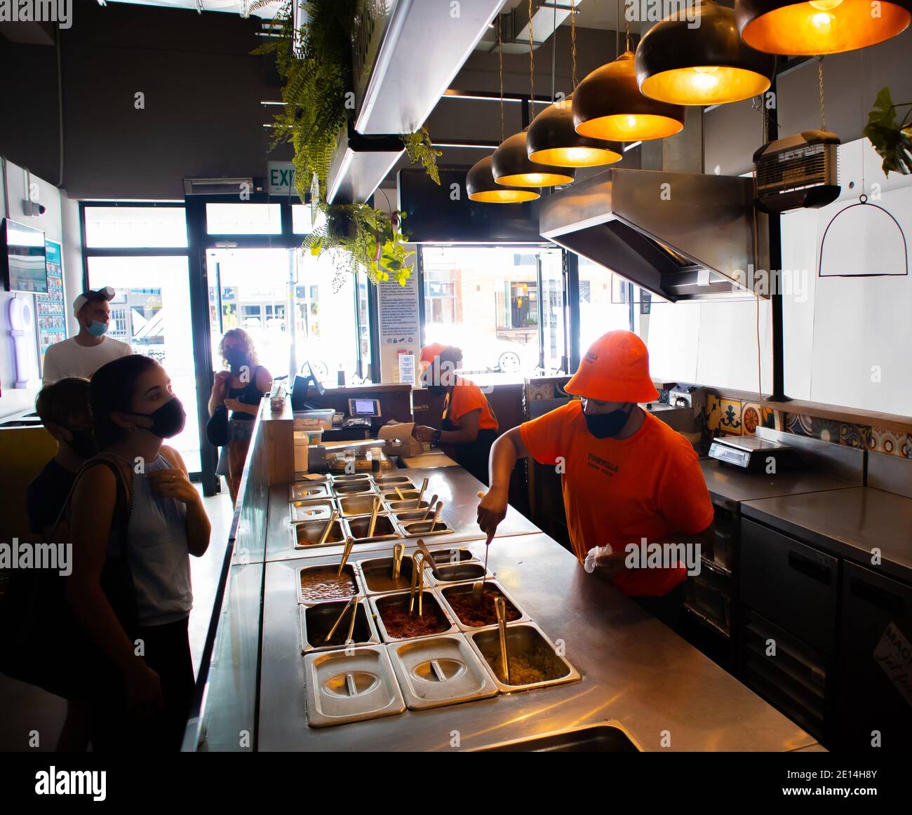 Mojo Markt- Kapstadt, Südafrika - 16/12/2020 Lebensmittelstand im Mojo Markt. Die Mitarbeiter tragen orangefarbene Outfits und Gesichtsmasken. Kreative Aufnahme. Stockfoto