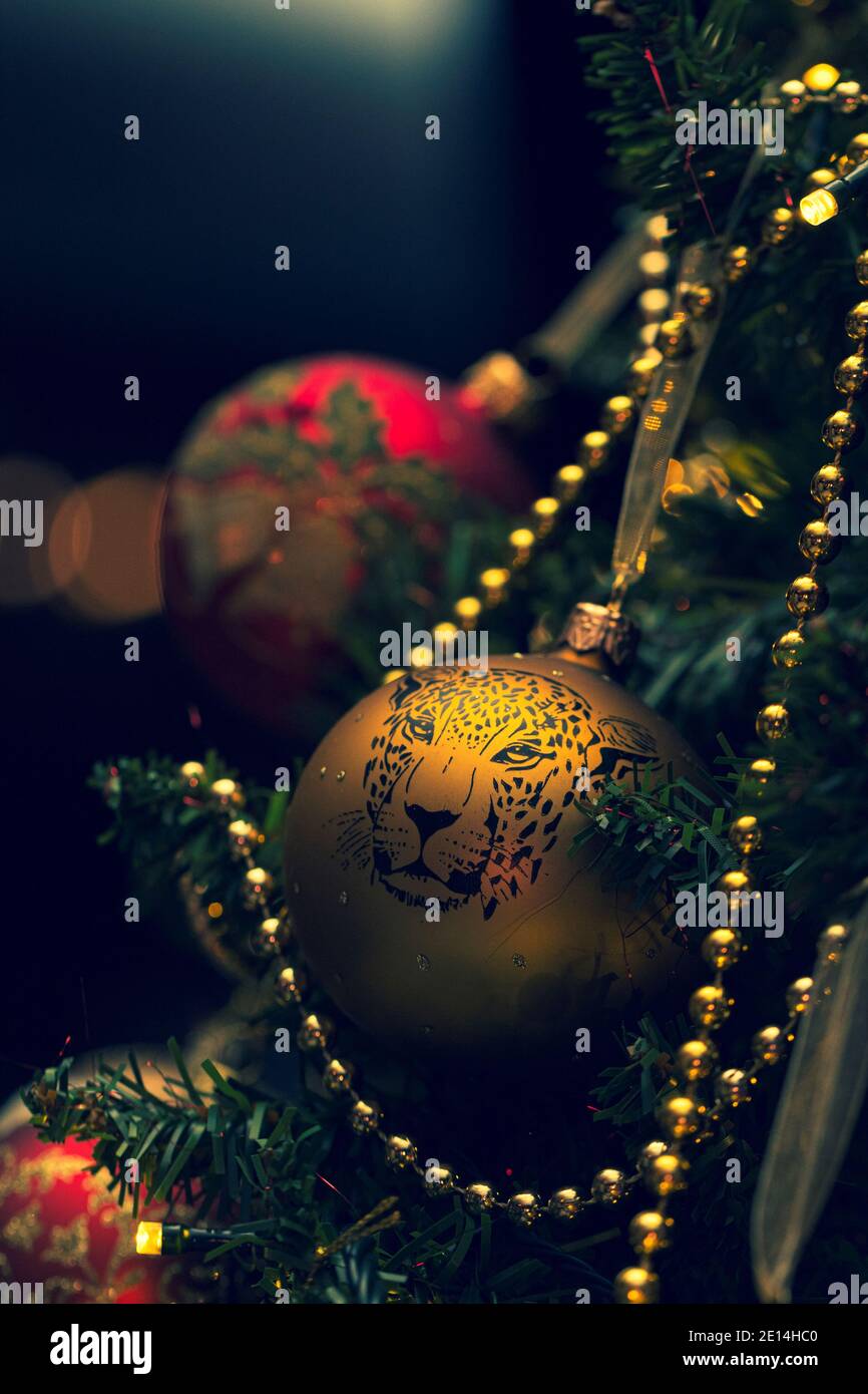 Ein Porträt einer seltenen gelben Glas weihnachtskugel mit einem Druck von einem Leoparden auf ihm und kleinen funkelnden Diamanten. Das Ornament hängt an einem Baum und s Stockfoto