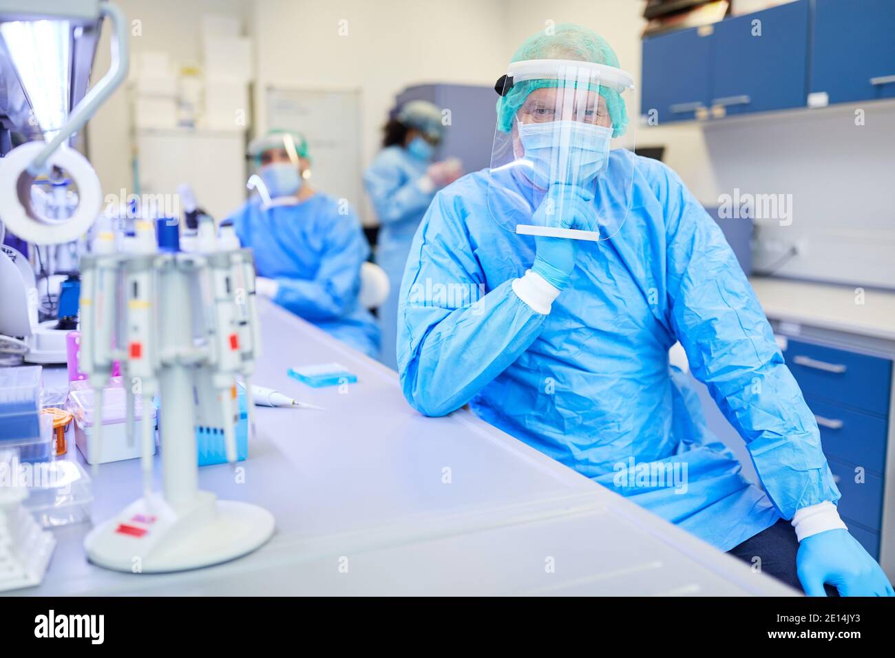 Forscher in Schutzkleidung im Biotechnologielabor mit medizinischem Team Im Hintergrund Stockfoto
