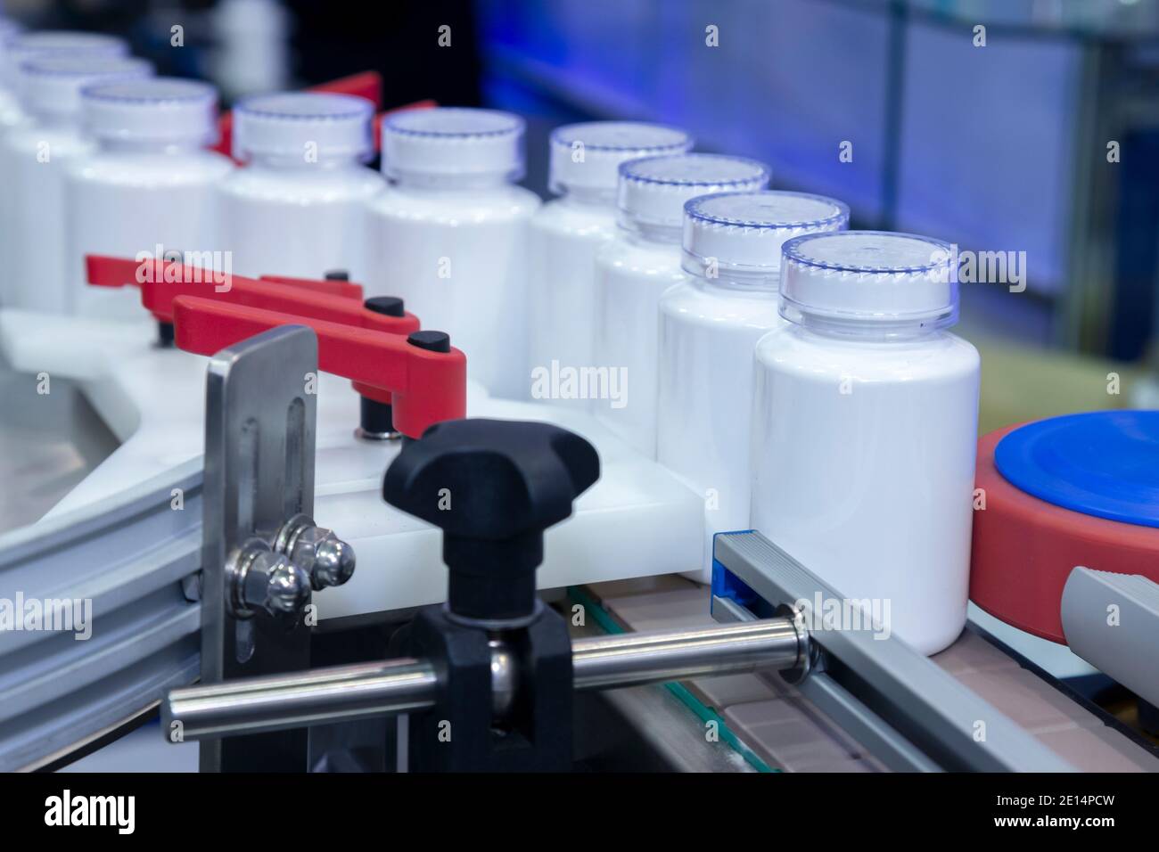 Weiße Medizin Plastikflasche auf Produktionslinie des Förderers an der Abfüllmaschine in der medizinischen Fabrik. Selektiver Fokus. Pharmazeutische Herstellung und Stockfoto