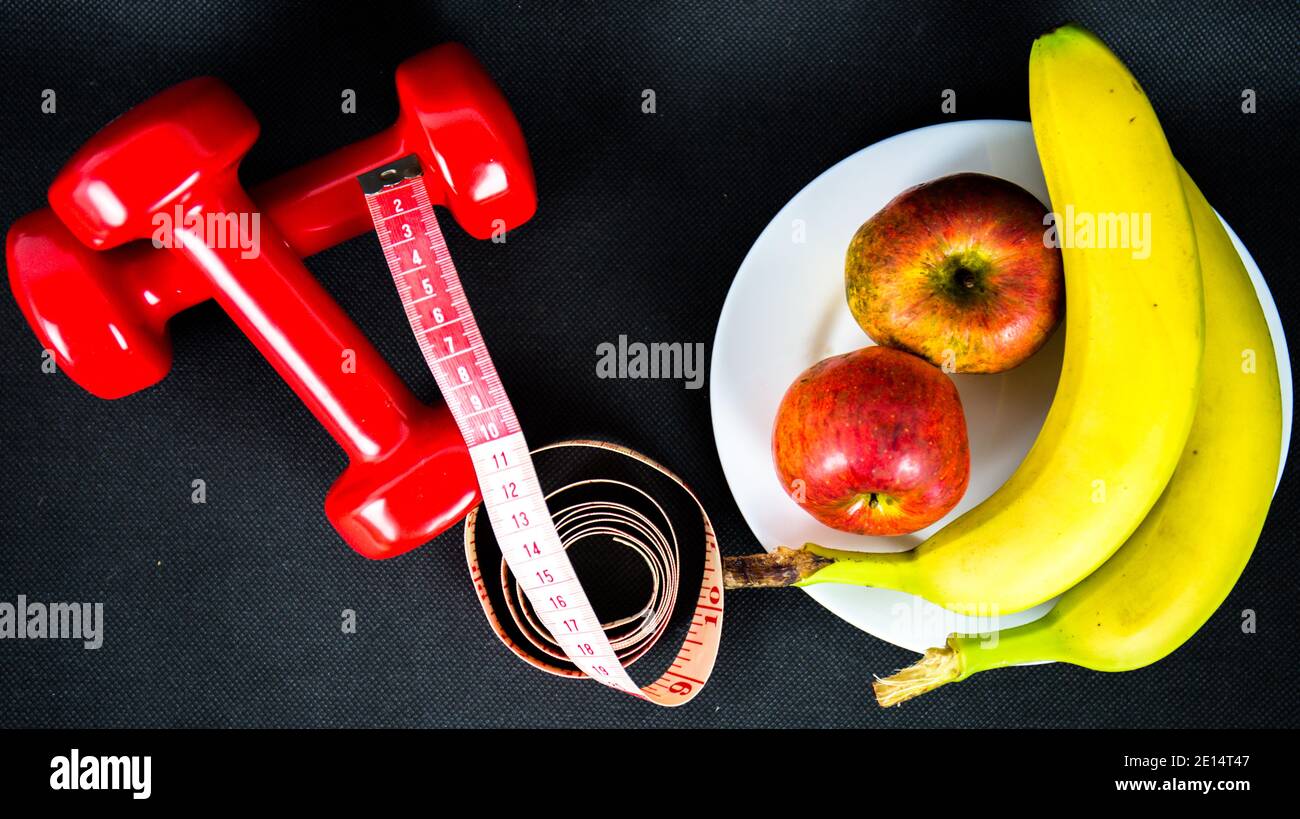 Gewichtsverlust-Programm mit niedrigen Kalorien und täglichen Übungen. Ernährung und Taillenumfang Reduktion mit gesunden Obst und Hantel-Training Stockfoto