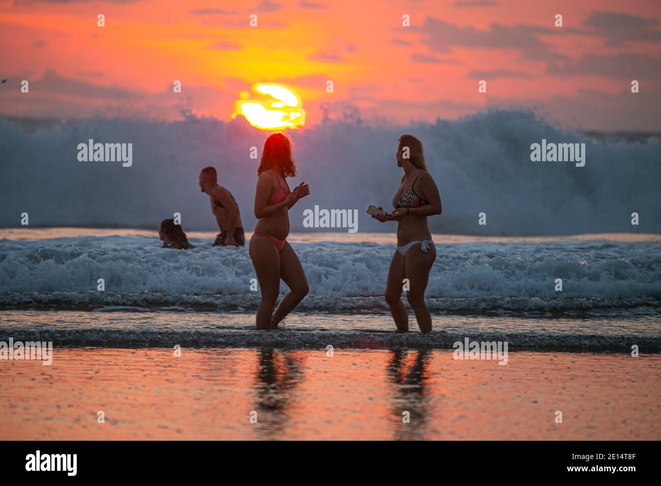 Zwei Frauen am Strand bei Sonnenuntergang in Kuta Beach von Bali, mit Blick auf das Meer Stockfoto
