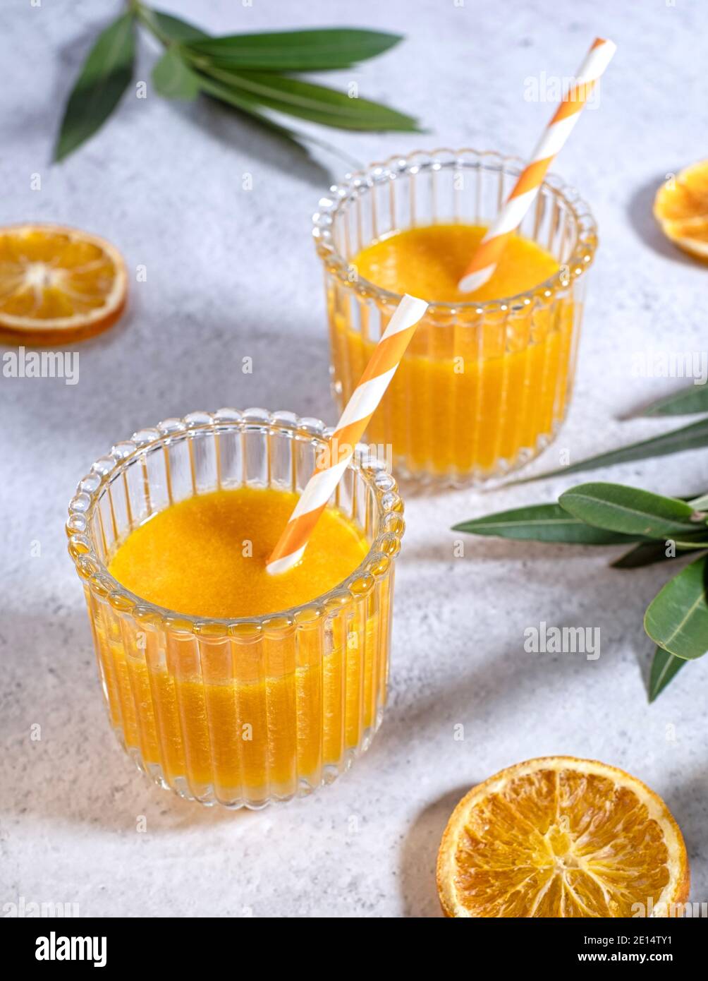 Frisch zubereitetes Orangensaft, wunderschön in zwei Gläsern auf einem Marmortisch angeordnet, Draufsicht, Portrait, Stockfoto