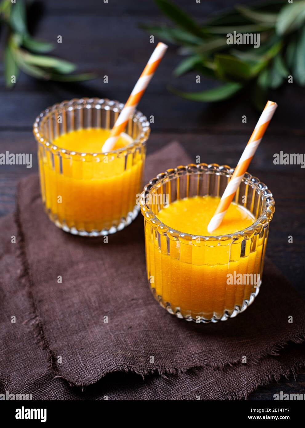 Frisch gebackene Orangensaft wunderschön in zwei Gläsern auf einem Holztisch angeordnet, Draufsicht, Portrait, Stockfoto