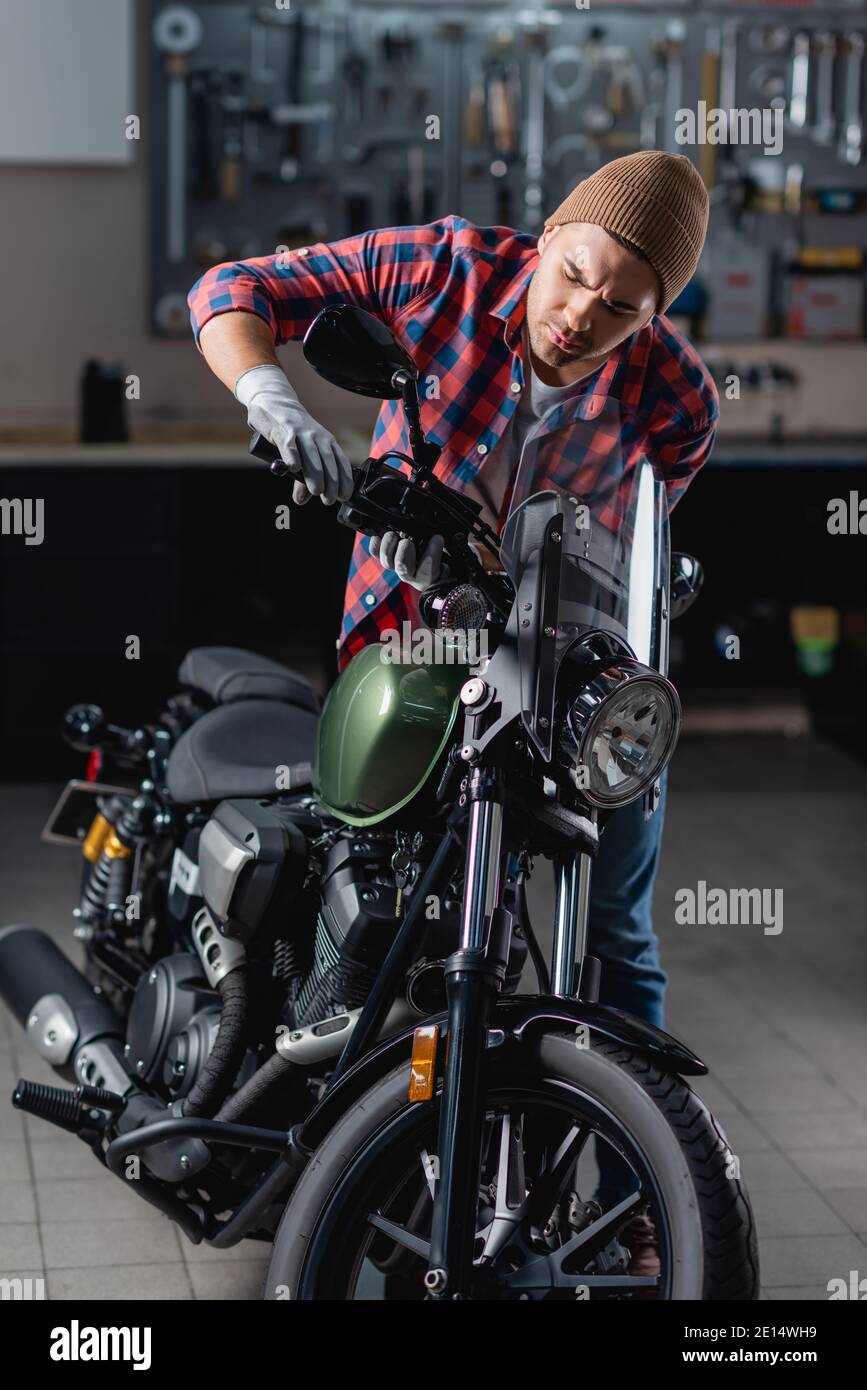 Mechaniker in kariertem Hemd und Handschuhen, die den Bremsgriff untersuchen Motorradlenker Stockfoto