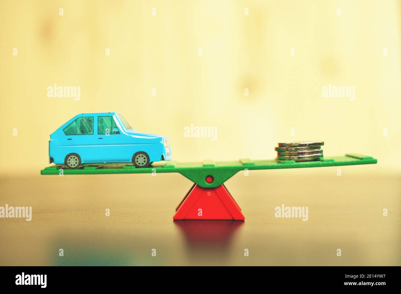 Konzept der Balance zwischen Auto und Geld auf gelbem Hintergrund. Nahaufnahme, selektiver Fokus Stockfoto