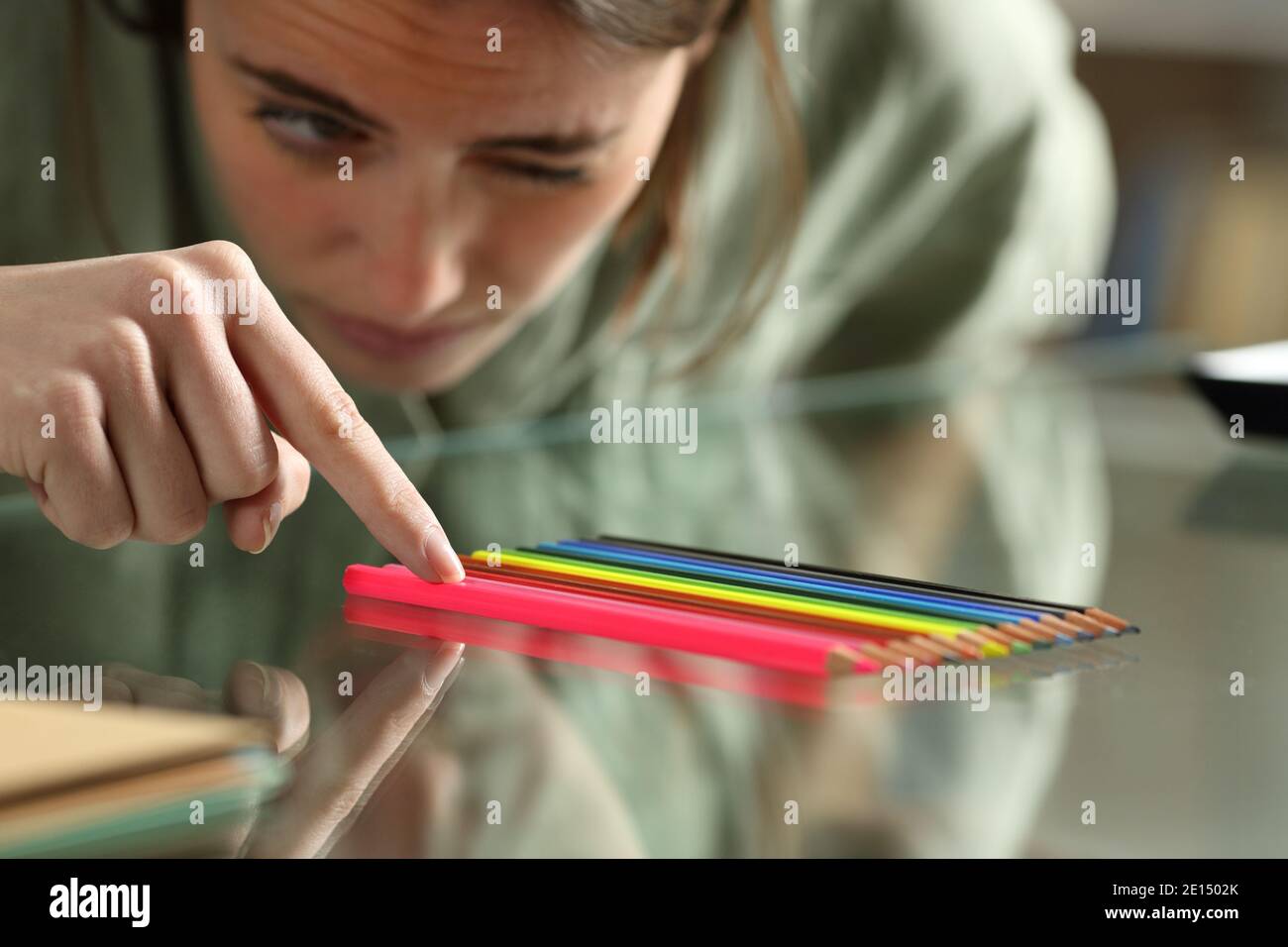 Zwanghafte Frau, die Bleistifte genau auf einem Glas ausrichtet Tabelle Stockfoto