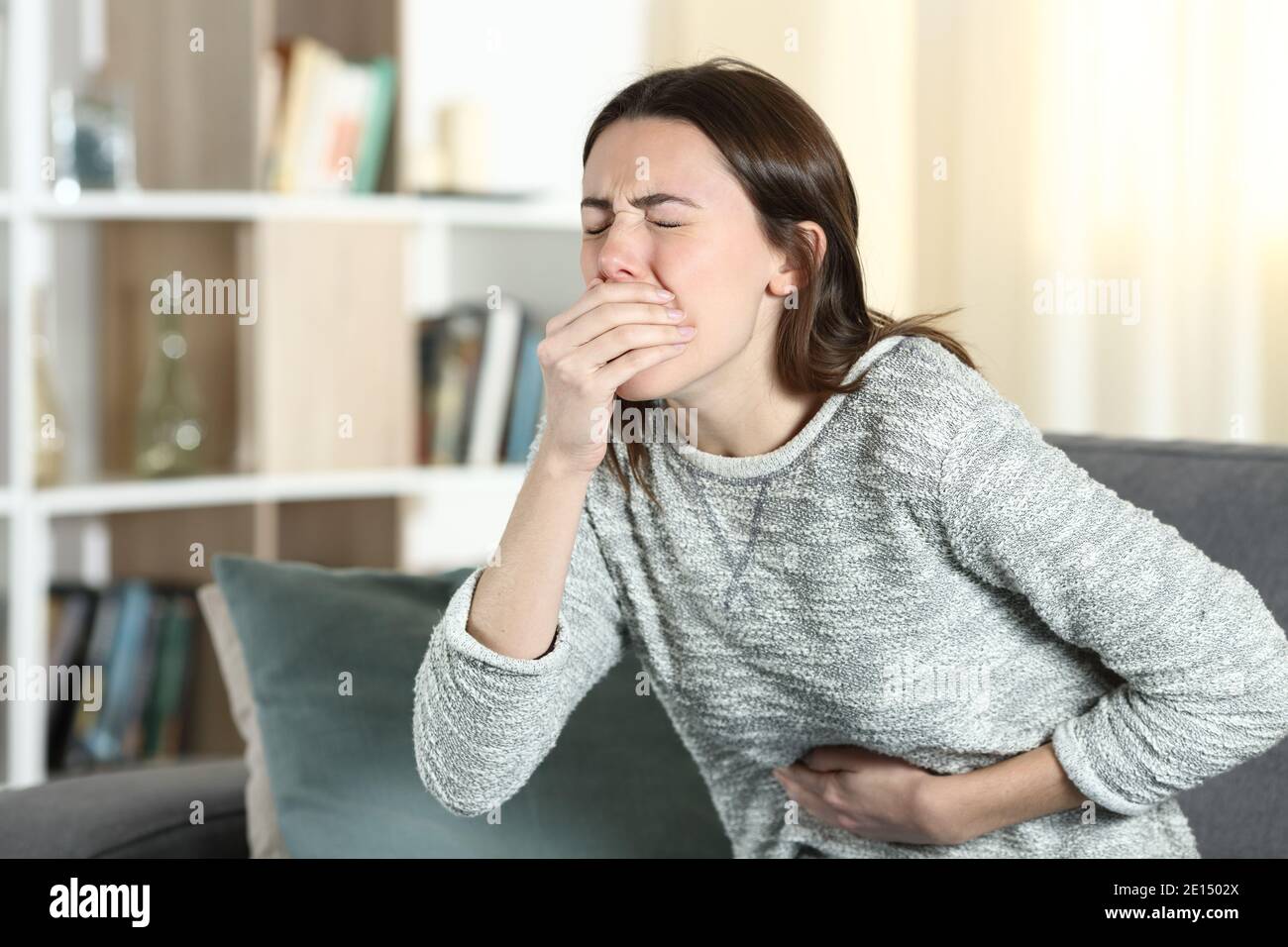 Gestresste Frau mit Bauchschmerzen im Begriff, sich zu erbrechen Eine Couch zu Hause Stockfoto