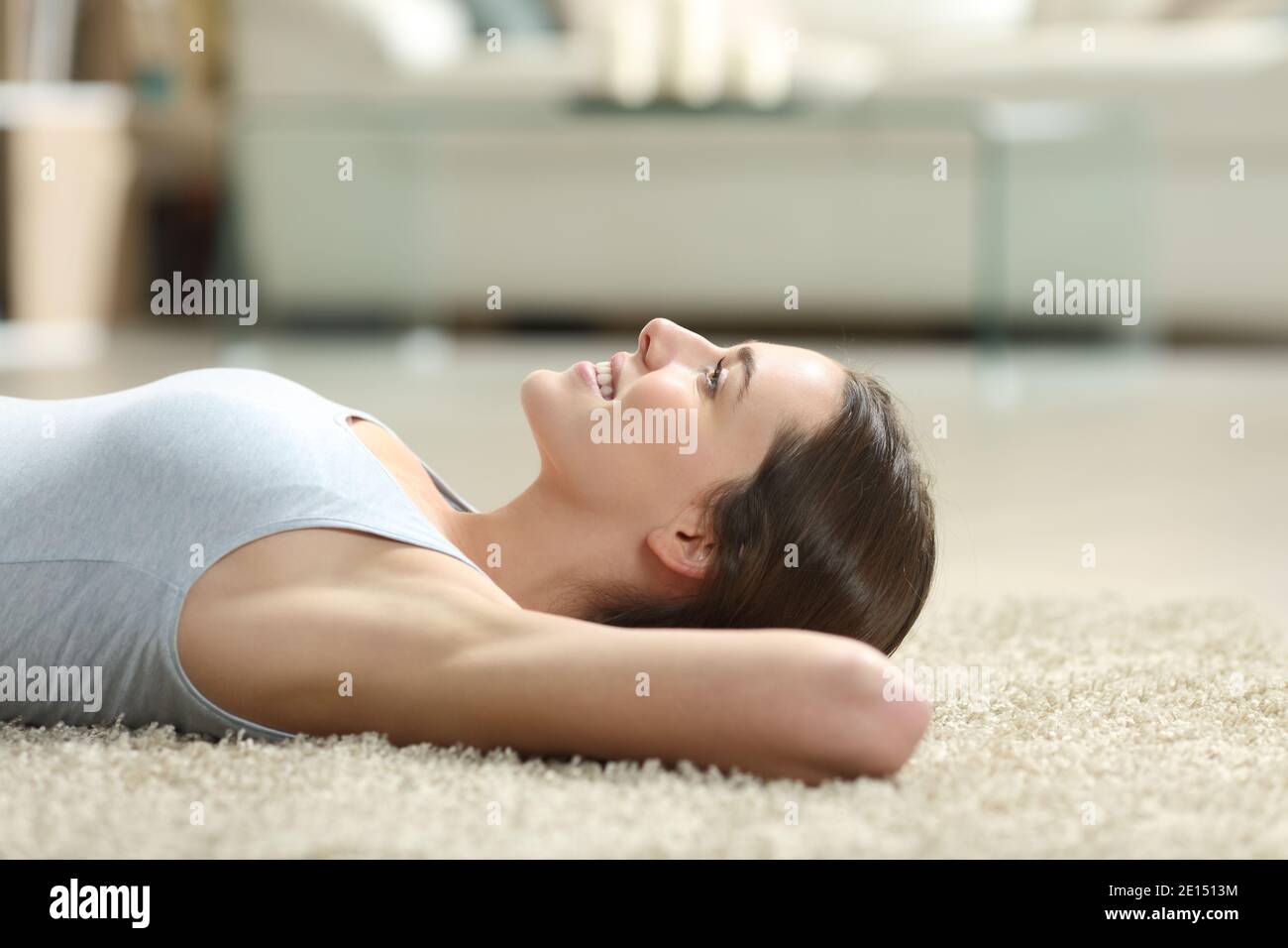 Seitenansicht Porträt einer glücklichen Frau entspannend mit gewachst Achselhöhlen liegen auf einem Teppich zu Hause Stockfoto
