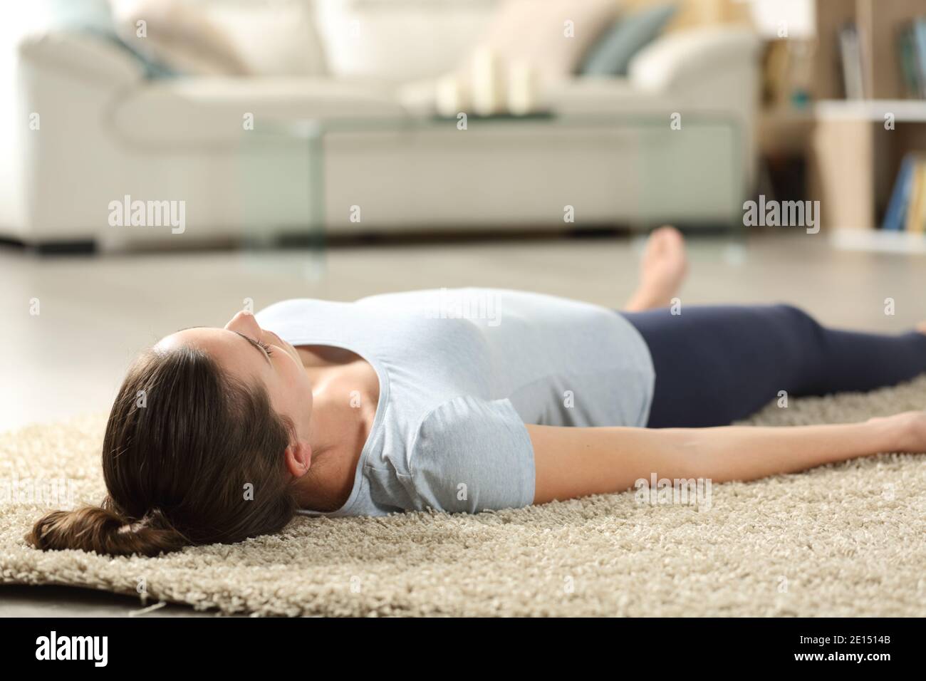 Frau entspannt savasana Yoga Pose liegend auf einem Teppich Zu Hause Stockfoto