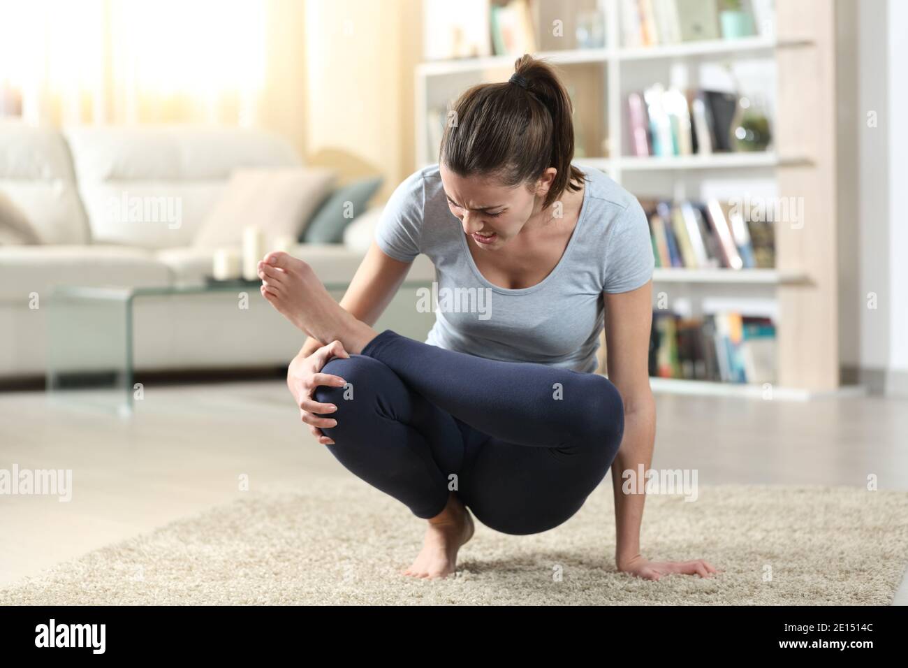 Frau leiden Knieschmerzen, während tut Yoga-Übung auf Der Boden zu Hause Stockfoto