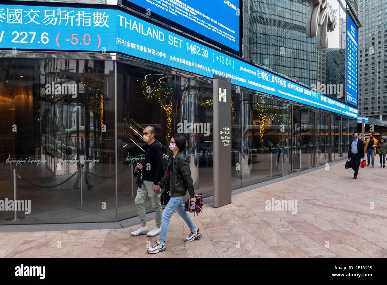 Fußgänger, die Gesichtsmasken tragen, gehen an einer Börsenauslage vorbei, die den ersten Tag des 2021-jährigen Hang Seng Index-Ergebnisses in Hongkong zeigt. Stockfoto