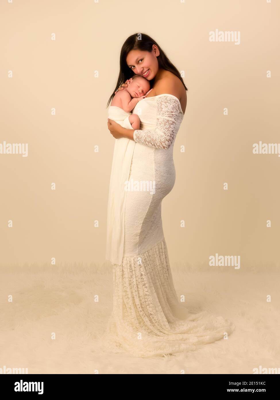 Schöne junge Mutter in einem weißen Spitzenkleid posiert mit Ihr 7 Tage alter neugeborener Sohn Stockfoto