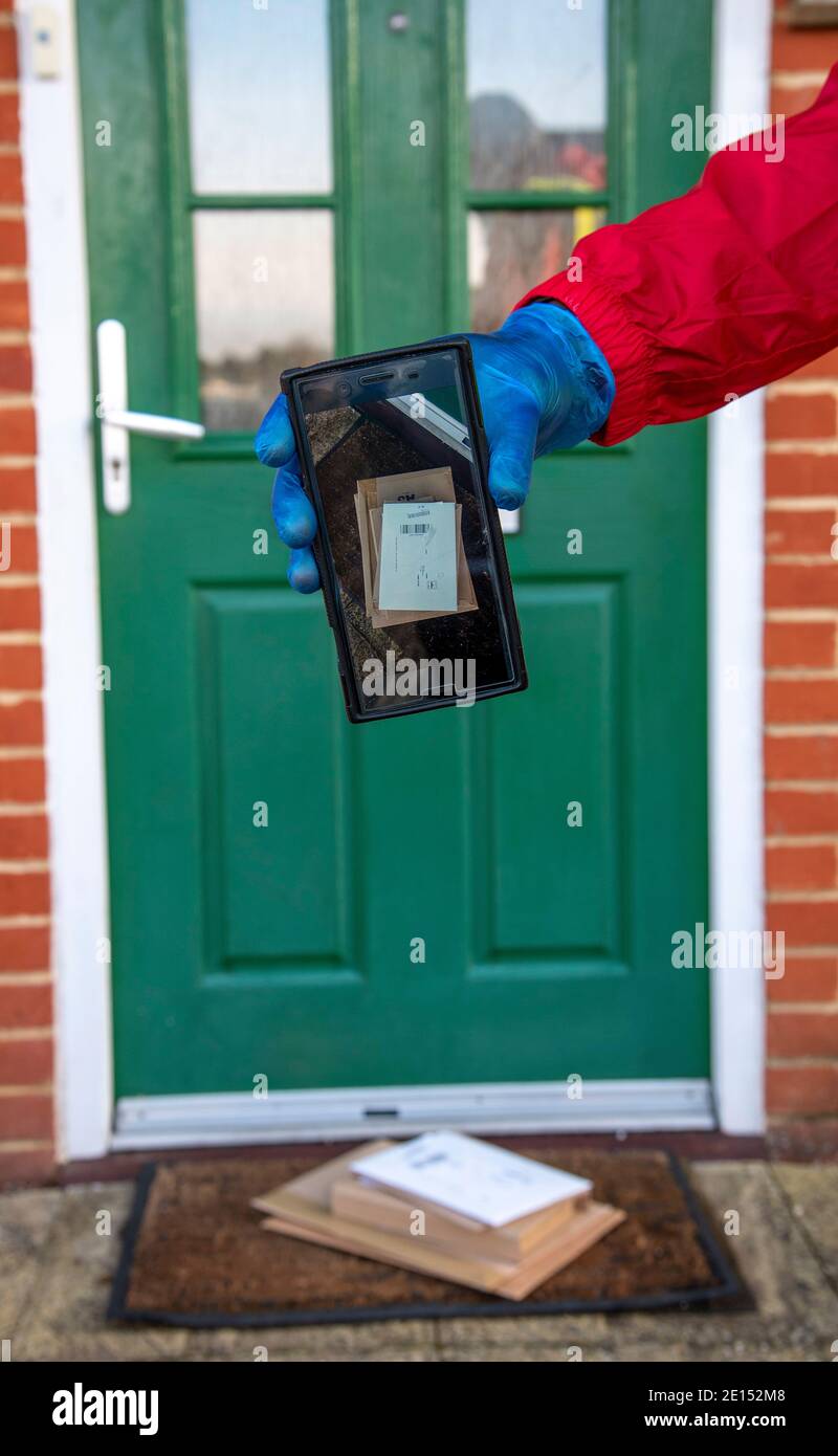 Hampshire, England, Großbritannien. 2020, Male Kurier Pakete und Pakete während der Covid-19 Epidemie tragen Handschuhe und eine Maske. Aufnahme auf mobilem Pho Stockfoto