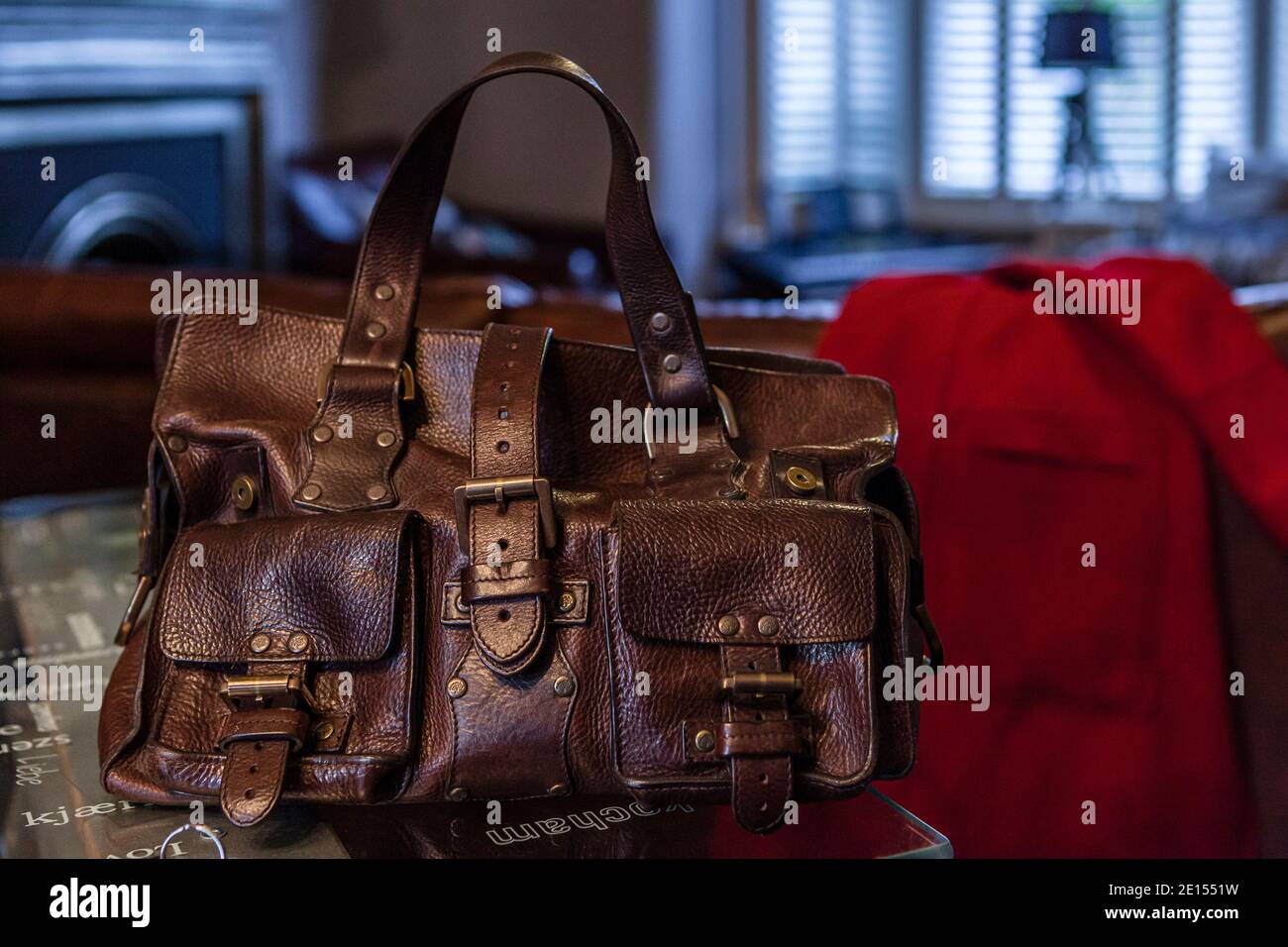 Vintage Designer braune Leder Handtasche auf Schreibtisch in der Lounge  neben Roter Mantel Stockfotografie - Alamy