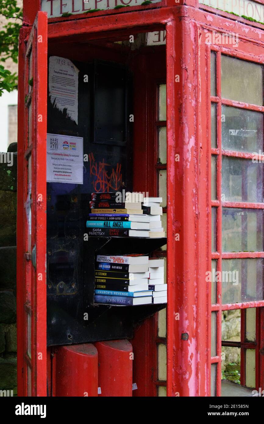 Ein verlassener Kiosk mit roten Telefonen ist zu einer temporären Bibliothek geworden, in der Menschen Bücher ausleihen können, Harrogate, North Yorkshire, Großbritannien. Stockfoto