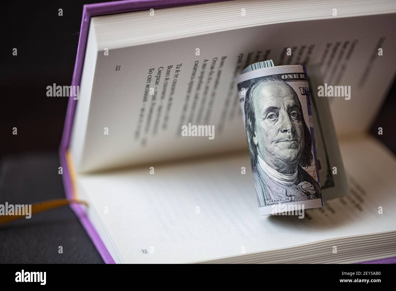 Rolle von 100-Dollar-Banknoten in violettem Buch Stockfoto
